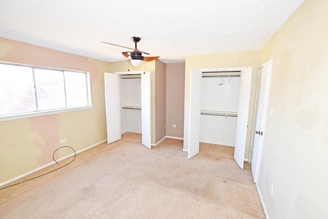 unfurnished bedroom with light carpet, ceiling fan, and multiple closets