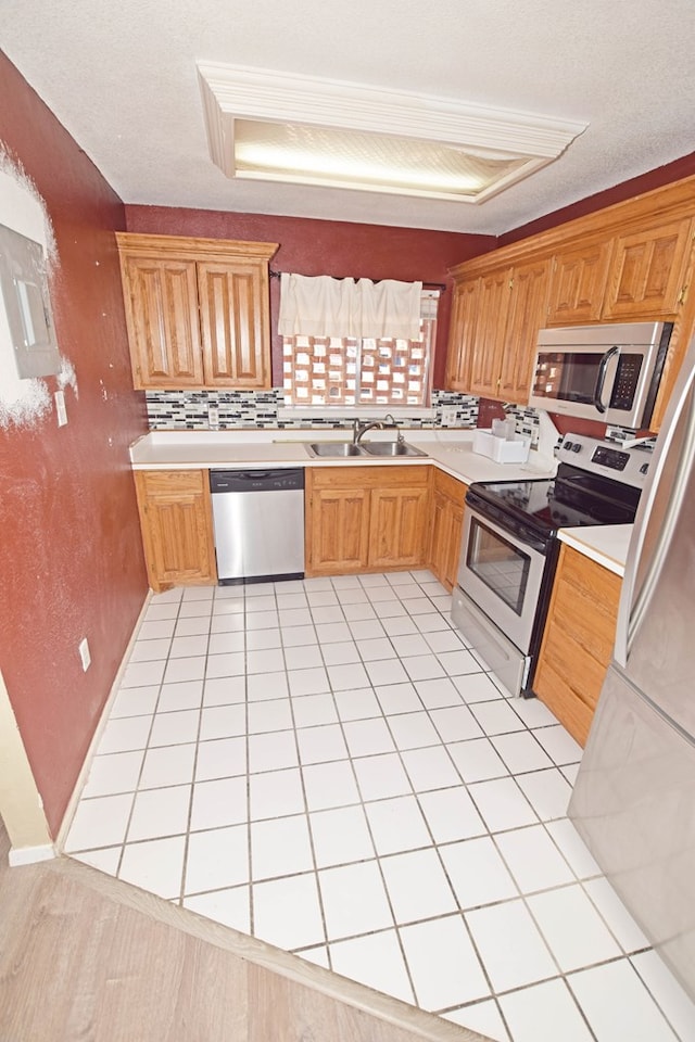 kitchen with light tile patterned flooring, appliances with stainless steel finishes, tasteful backsplash, and a textured ceiling