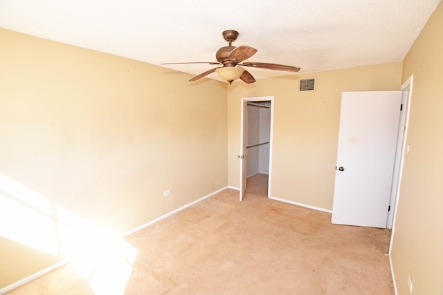 unfurnished bedroom featuring ceiling fan, light colored carpet, a textured ceiling, and a closet