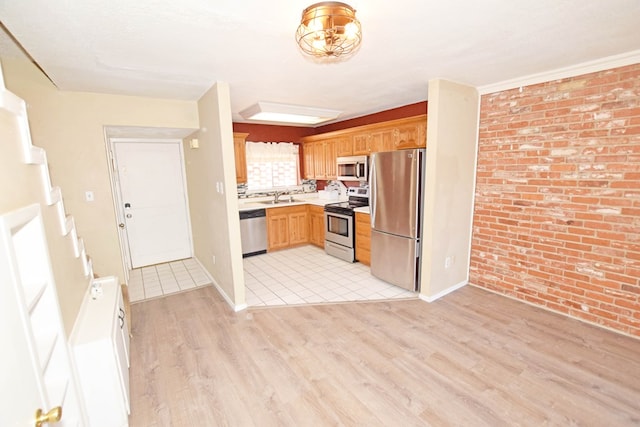 kitchen featuring sink, light hardwood / wood-style flooring, stainless steel appliances, and brick wall