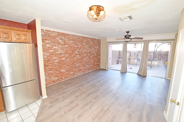 unfurnished living room with crown molding, brick wall, ceiling fan, and light hardwood / wood-style flooring