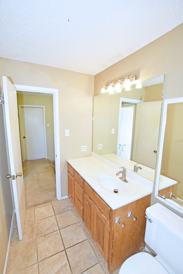 bathroom featuring tile patterned flooring, vanity, a textured ceiling, and toilet