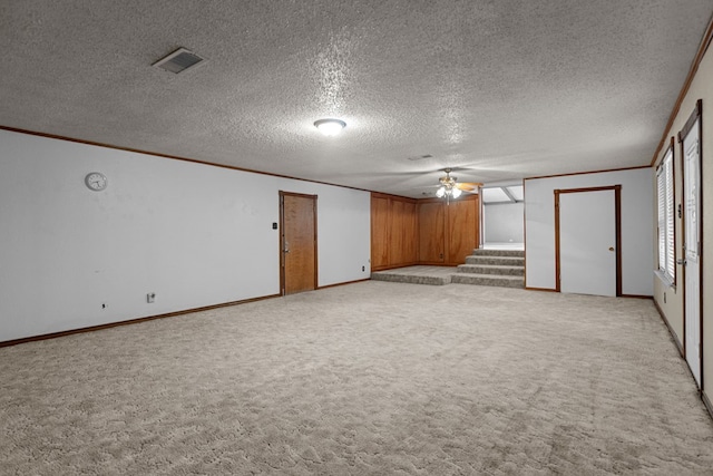 carpeted spare room featuring a textured ceiling, ceiling fan, and ornamental molding