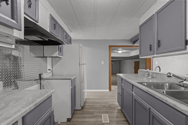 kitchen with gray cabinets, sink, a textured ceiling, and light wood-type flooring