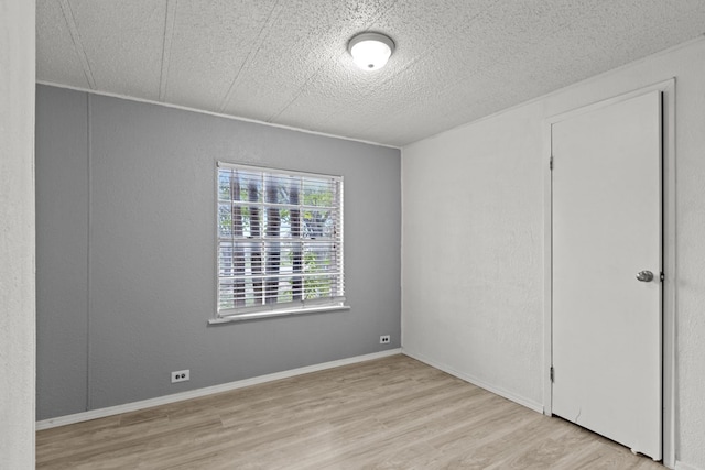 spare room featuring a textured ceiling and light wood-type flooring