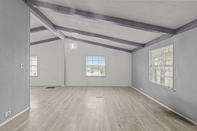 spare room with vaulted ceiling with beams and light hardwood / wood-style floors