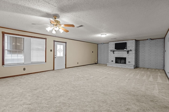 unfurnished living room with ceiling fan, a textured ceiling, light carpet, and a brick fireplace