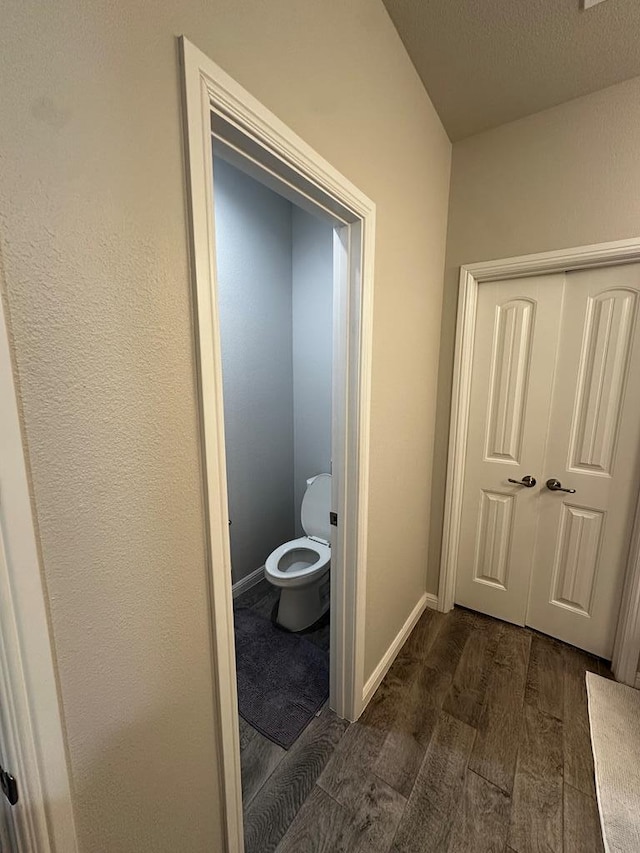 bathroom with toilet, baseboards, and wood finished floors