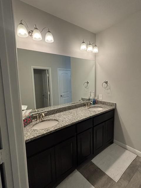 full bath featuring double vanity, a sink, and baseboards