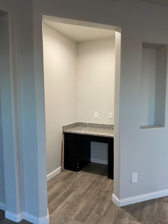 interior space featuring baseboards, wood finished floors, and built in study area