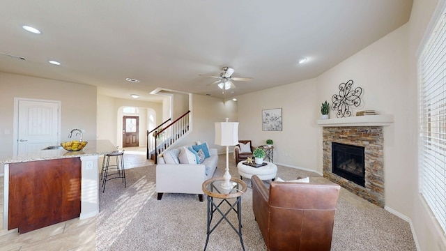 carpeted living room featuring ceiling fan, a fireplace, and sink