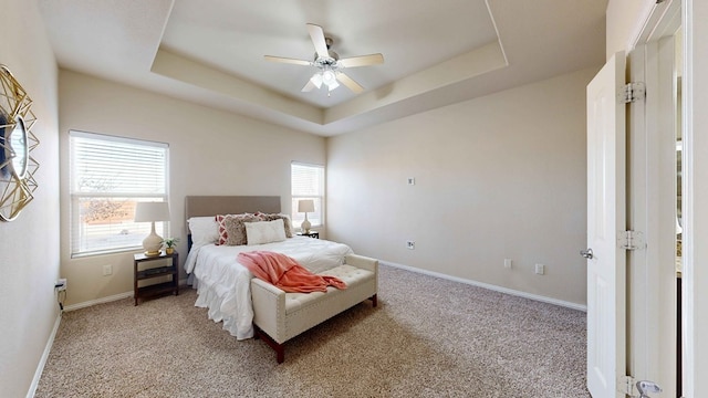 bedroom with a raised ceiling, ceiling fan, and light carpet