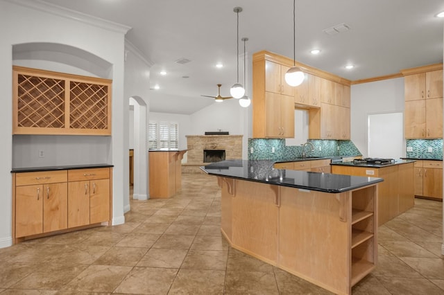 kitchen featuring sink, a center island, light brown cabinets, crown molding, and decorative light fixtures