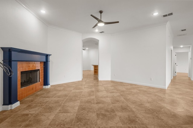 unfurnished living room featuring ceiling fan, crown molding, and a tiled fireplace