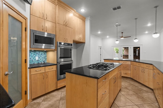 kitchen featuring ceiling fan, hanging light fixtures, decorative backsplash, a kitchen island, and appliances with stainless steel finishes