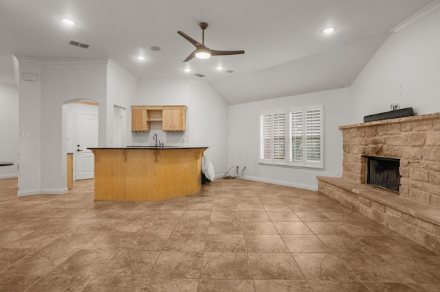 kitchen with ornamental molding, ceiling fan, a breakfast bar area, a fireplace, and lofted ceiling