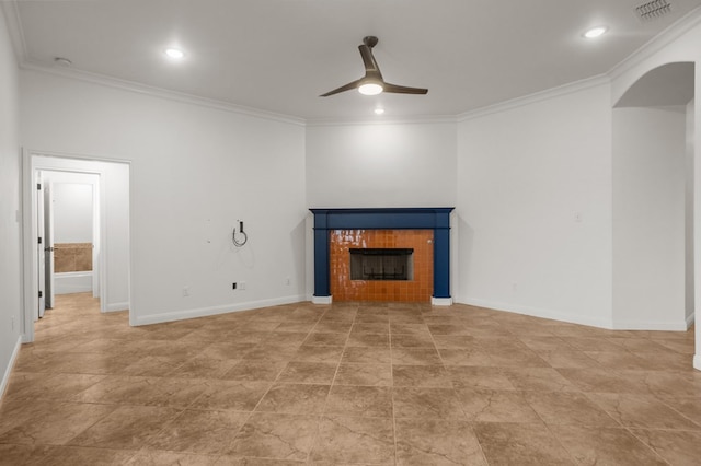 unfurnished living room with a tile fireplace, crown molding, and ceiling fan