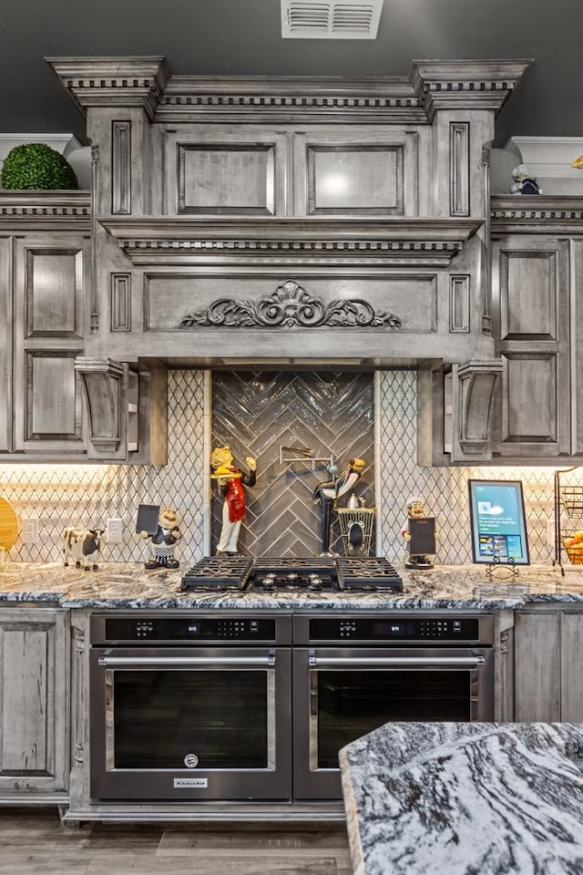 kitchen featuring decorative backsplash, oven, and stone countertops