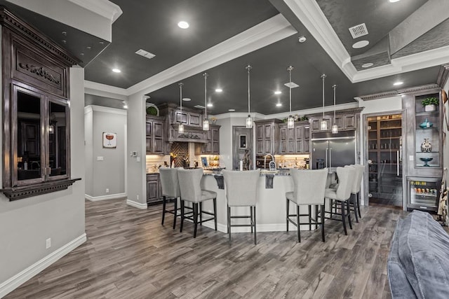 kitchen featuring pendant lighting, dark brown cabinetry, a large island, and stainless steel built in fridge