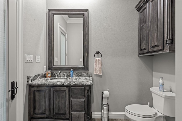 bathroom featuring vanity, wood-type flooring, ornamental molding, and toilet