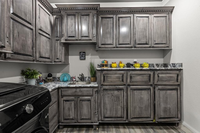 kitchen with black stove, dark brown cabinets, sink, and dark wood-type flooring