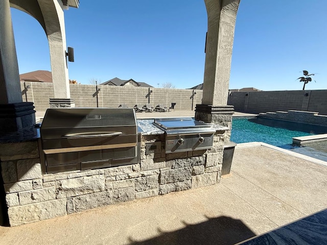 view of patio with a fenced in pool, an outdoor kitchen, and a grill