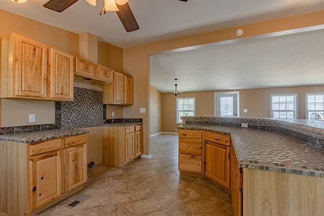 kitchen featuring ceiling fan with notable chandelier, backsplash, a wealth of natural light, and vaulted ceiling