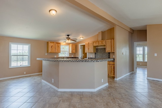 kitchen with light brown cabinets, vaulted ceiling, and plenty of natural light