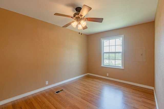 spare room with ceiling fan, light hardwood / wood-style floors, and electric panel