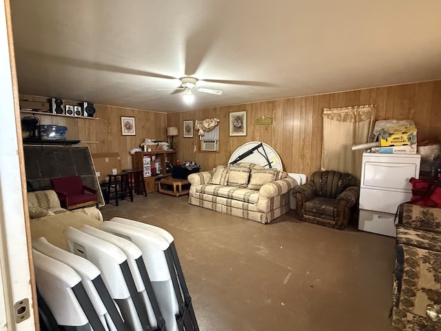 living room with wood walls, ceiling fan, concrete floors, and washer / dryer