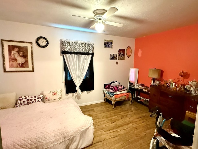 bedroom featuring ceiling fan, wood-type flooring, and a textured ceiling