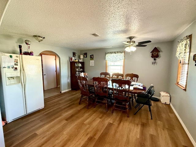 dining space with ceiling fan, a textured ceiling, and hardwood / wood-style flooring