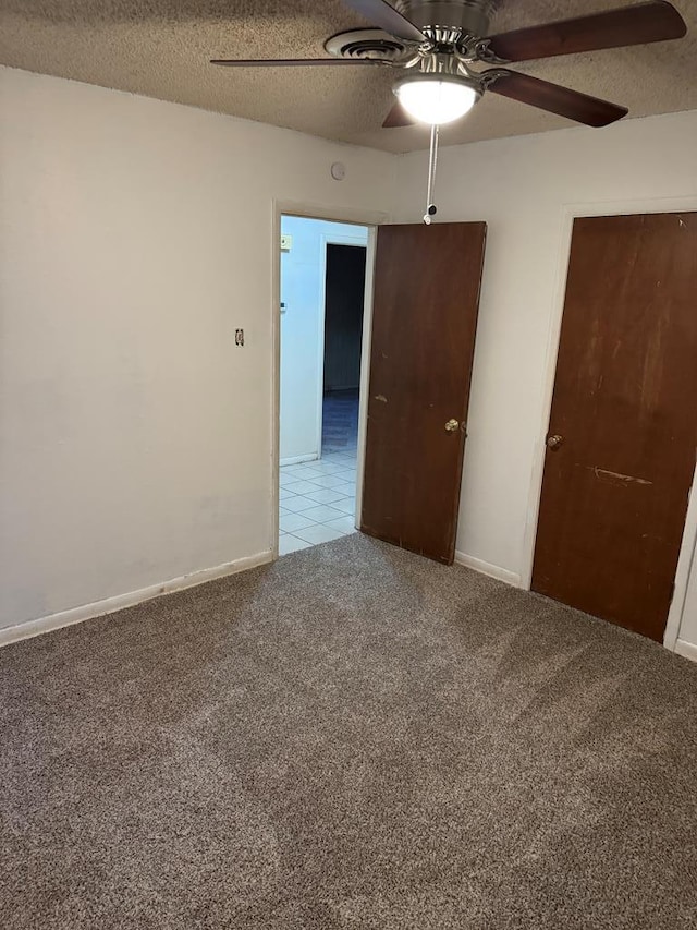 unfurnished bedroom featuring light carpet, a textured ceiling, a ceiling fan, and baseboards