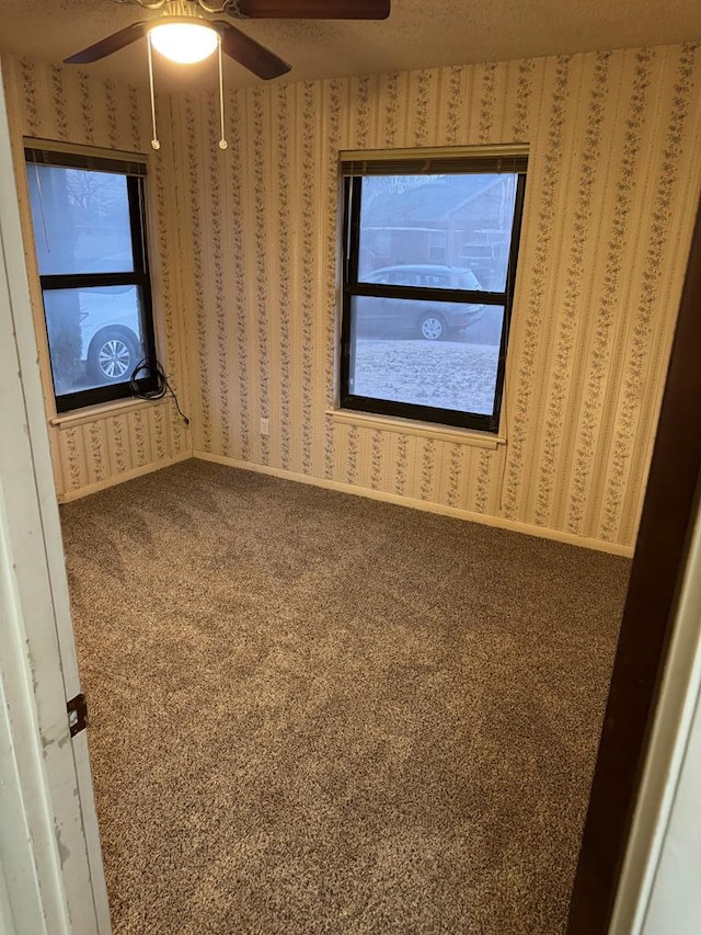 carpeted spare room featuring baseboards, ceiling fan, and wallpapered walls