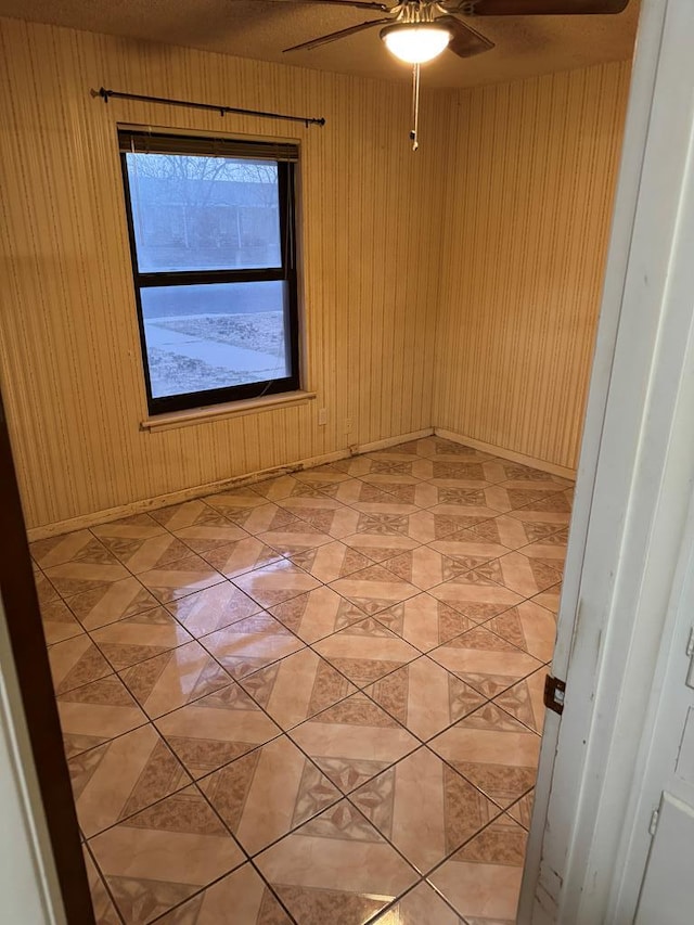 unfurnished room featuring light tile patterned floors, ceiling fan, and baseboards