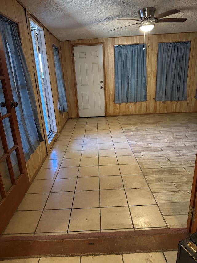 foyer featuring a textured ceiling, light tile patterned floors, and wood walls