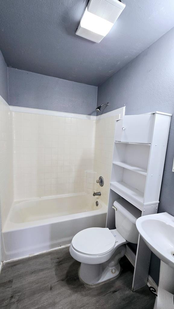 full bathroom with bathing tub / shower combination, sink, wood-type flooring, and toilet