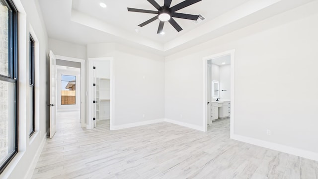 empty room with light wood finished floors, baseboards, ceiling fan, a tray ceiling, and recessed lighting