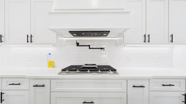 kitchen featuring stainless steel gas stovetop, white cabinetry, light countertops, and decorative backsplash