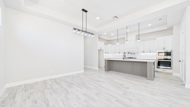 kitchen featuring stainless steel appliances, a raised ceiling, light countertops, and white cabinets