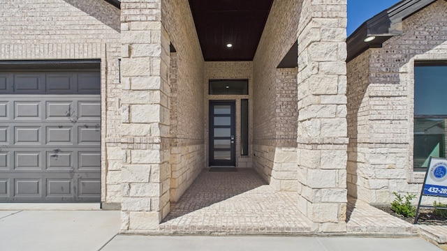 doorway to property featuring a garage, stone siding, and brick siding