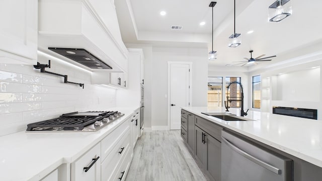 kitchen with tasteful backsplash, custom range hood, visible vents, appliances with stainless steel finishes, and a sink