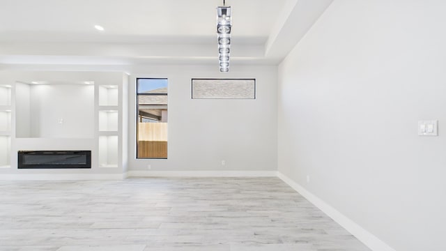 interior space with baseboards, wood finished floors, and a glass covered fireplace