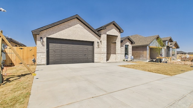 view of front of property with an attached garage, brick siding, fence, concrete driveway, and a gate