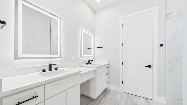 full bath featuring double vanity, baseboards, a sink, and wood finished floors