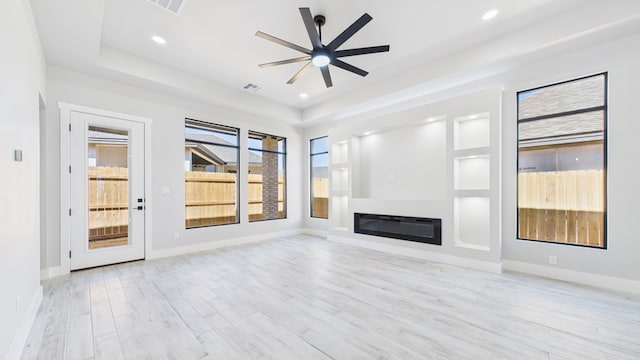 unfurnished living room with light wood-style floors, recessed lighting, baseboards, and a glass covered fireplace