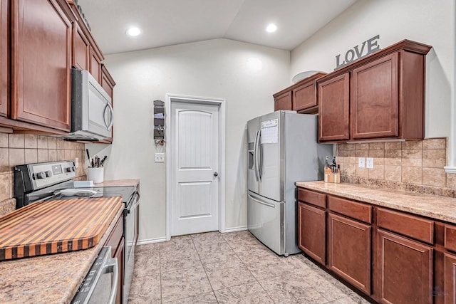 kitchen with light stone countertops, appliances with stainless steel finishes, tasteful backsplash, and vaulted ceiling