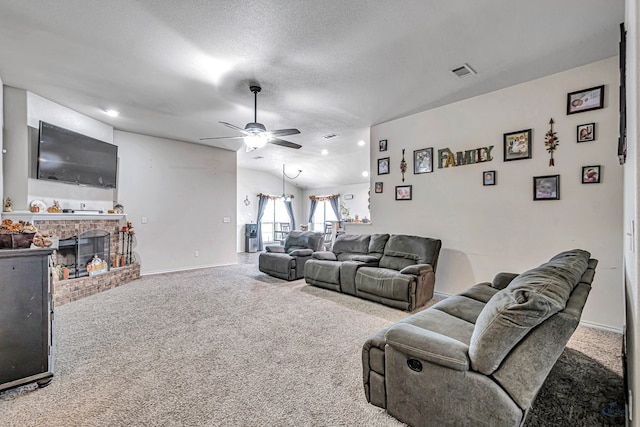 living room featuring carpet flooring, ceiling fan, a fireplace, and a textured ceiling