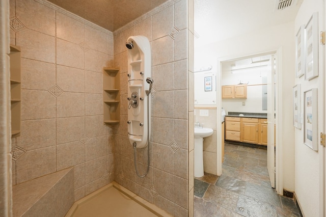 full bathroom with visible vents, stone tile flooring, and tiled shower