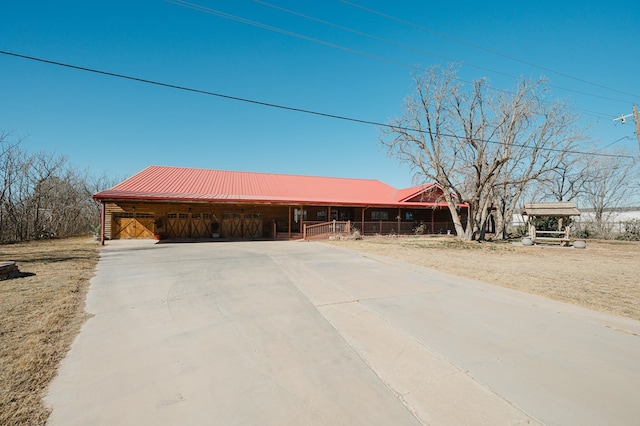 view of front facade with metal roof, concrete driveway, and an outdoor structure